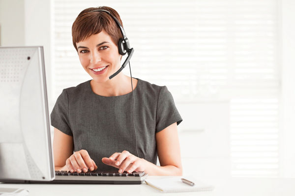 Short haired businesswoman sitting at a desk, wearing a headset