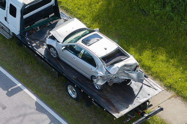 Flatbed tow truck hauling smashed vehicle