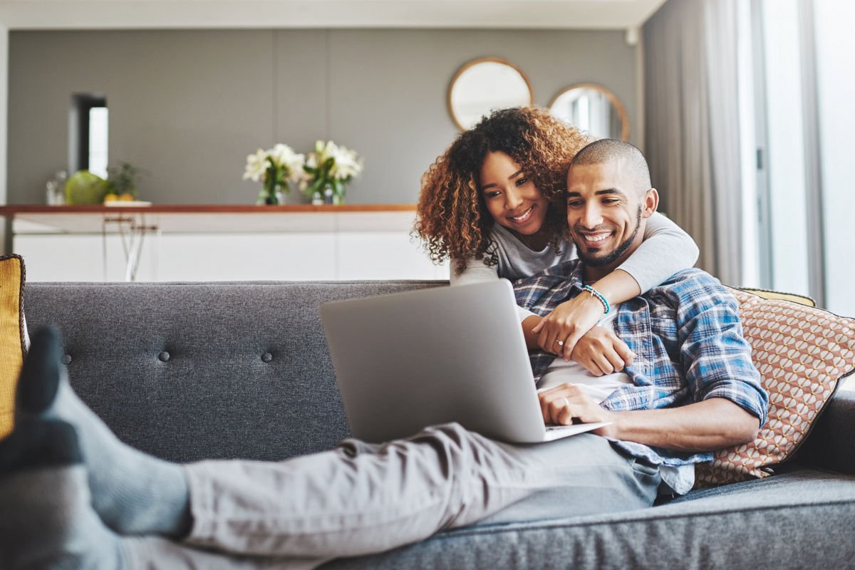 Couple smiling together while using laptop