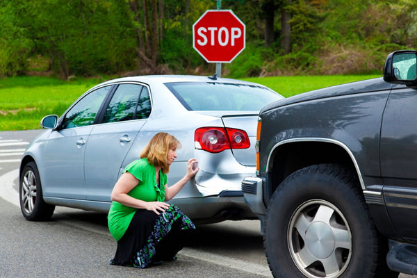 Woman inspecting damaged car
