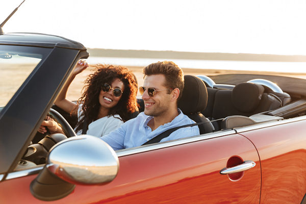 Couple in convertible driving sunset