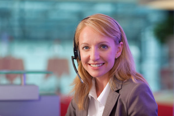 Friendly woman with headset at helpdesk in office building